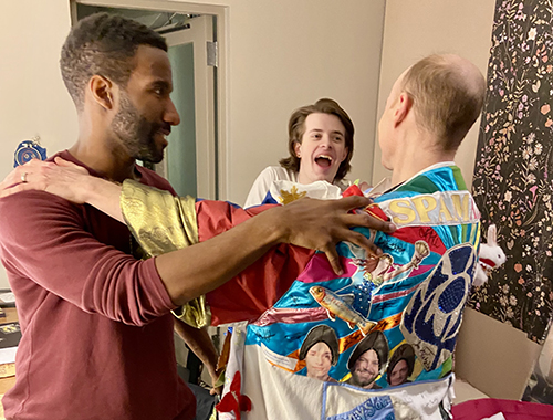 Davis's back is visible, in the Robe, as his arms reach out to both Clyde Voce and Cole Vaughn in a dressing room.