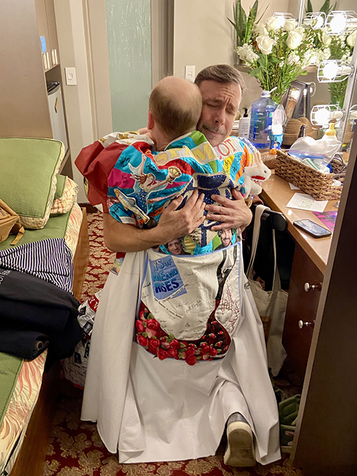 Davis's back is visible, in the Robe, as he embraces an emotional looking Wade McCollum, both of them kneeling on the floor of a dressing room.